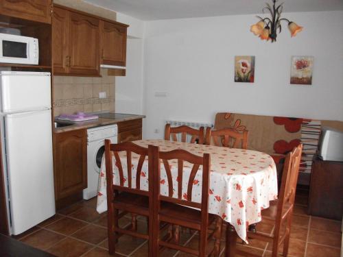 kuchnia ze stołem i krzesłami oraz białą lodówką w obiekcie Apartamentos Arcos de Solana w mieście Vilas del Turbon