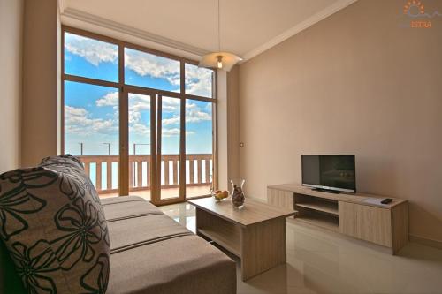 Una sala de estar con un sofá y un televisor. en Rotonda Inn Novigrad, en Novigrad Istria