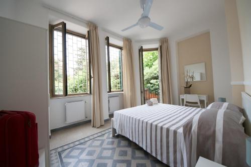 um quarto com uma cama com um cobertor listrado e janelas em Ostello San Luigi Orione em Anzio