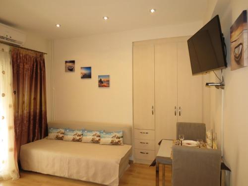 Schlafzimmer mit einem Bett, einem TV und einem Tisch in der Unterkunft Nice studio next to the sea in Athen