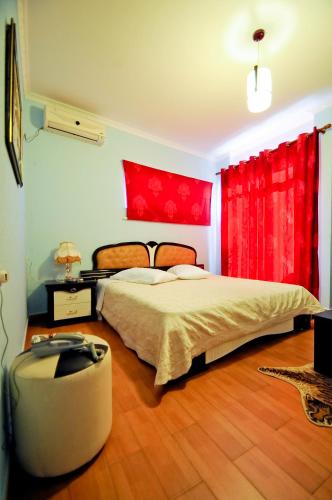 a bedroom with a large bed and red curtains at Hotel Lubjana in Tirana