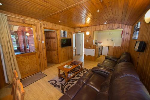 a living room with a leather couch and a table at Invercauld Lodges in Ballater