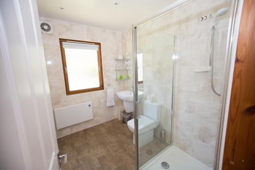 a bathroom with a toilet and a glass shower at Invercauld Lodges in Ballater