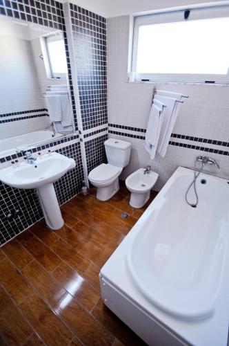 a bathroom with two sinks and a toilet and a tub at Hotel Lubjana in Tirana