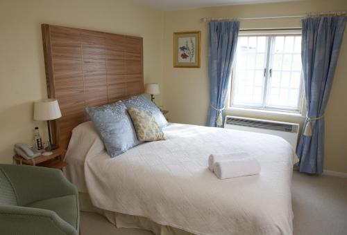 a bedroom with a bed and a chair and a window at Yalbury Cottage in Dorchester