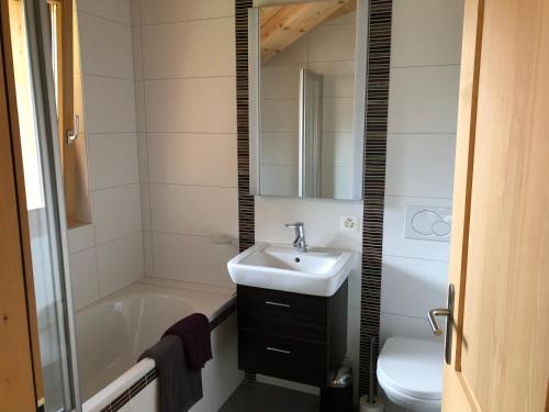 a bathroom with a sink and a tub and a toilet at Le Charme 9 in Morgins
