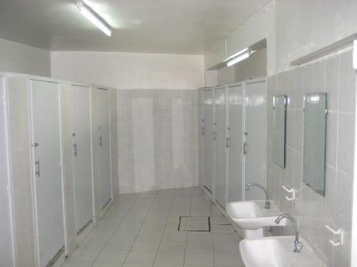 a white bathroom with two sinks and mirrors and stalls at Auberge De Jeunesse in Rabat