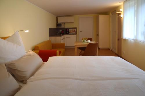 a bedroom with a white bed and a kitchen at Ferienquartier Goethe33 in Dresden