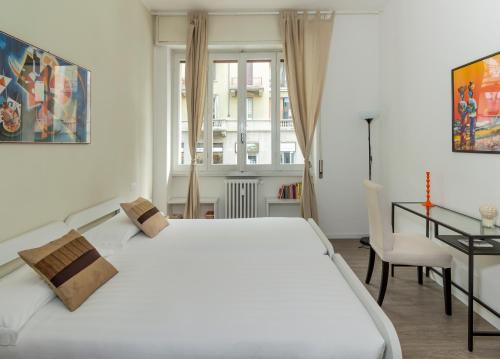 een slaapkamer met een groot wit bed en een bureau bij Milano Homey Apartment in Milaan