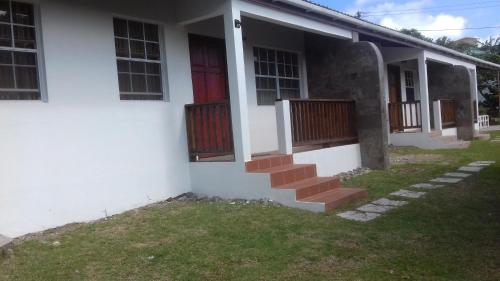 a white house with a red door and stairs at Habitat Apartments in Gros Islet