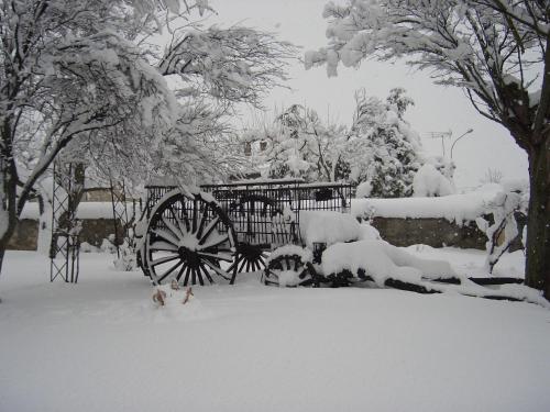 a snow covered carriage in a yard with trees at Posada del Indiano in Cidones