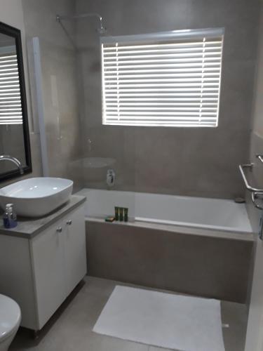 a bathroom with a tub and a sink and a toilet at The Coral Door in Vereeniging