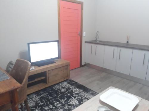 une cuisine avec une porte rouge et un bureau avec une télévision dans l'établissement The Coral Door, à Vereeniging