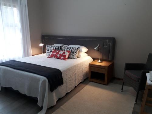 a bedroom with a bed and a lamp and a chair at The Coral Door in Vereeniging