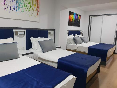 een hotelkamer met drie bedden met blauwe lakens bij Alican 2 in Izmir