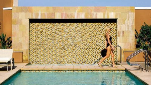 a woman is standing next to a swimming pool at Four Seasons Hotel Silicon Valley at East Palo Alto in Palo Alto
