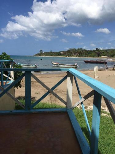 a blue railing next to a beach with boats in the water at Waikiki Guest House in Treasure Beach