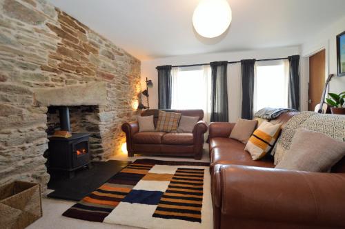 a living room with a couch and a stone fireplace at Gate Cottage in Tighnabruaich