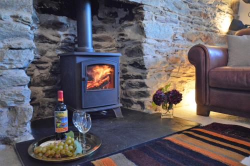 a wood stove in a living room with a bottle of wine at Gate Cottage in Tighnabruaich