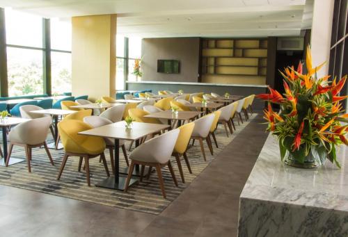 a dining room with tables and yellow chairs at Hotel Estelar Square in Medellín