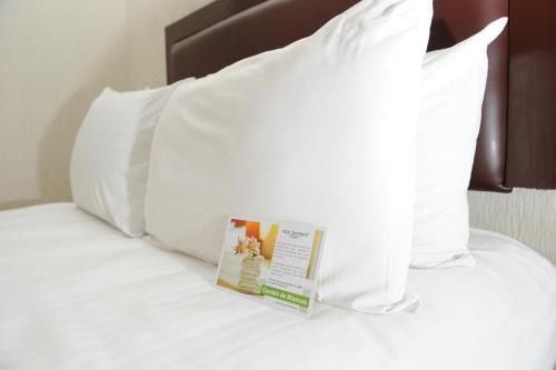 a book sitting on top of a bed with pillows at Imperio de Angeles Executive León Poliforum in León