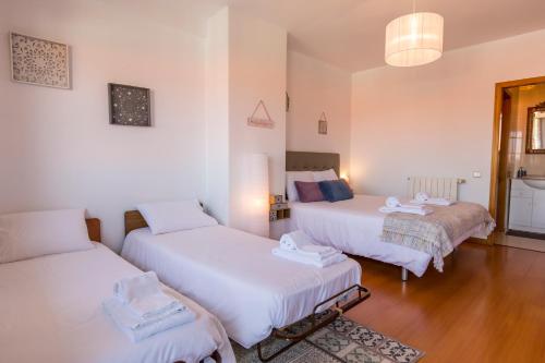 3 camas num quarto com paredes brancas e pisos em madeira em Sunset Relaxing Apt with terrace, parking & bikes em Porto