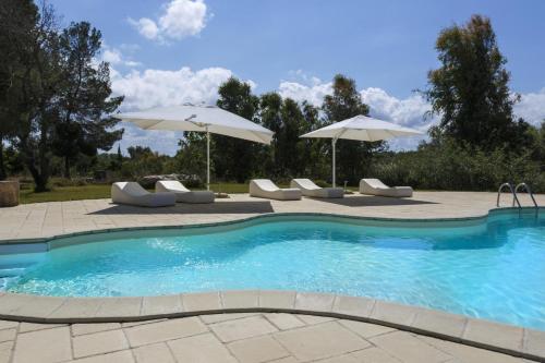 una piscina con sedie e ombrelloni su un patio di Villa Degli Eroi a Nardò