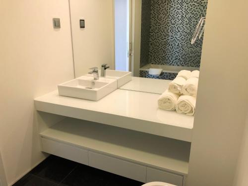 La salle de bains est pourvue d'un lavabo, d'un miroir et de serviettes. dans l'établissement Astro Vista Madeira Apartments, à Funchal