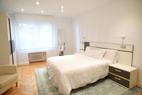 a white bedroom with a bed and a chair at SANTANDER CENTRO in Santander