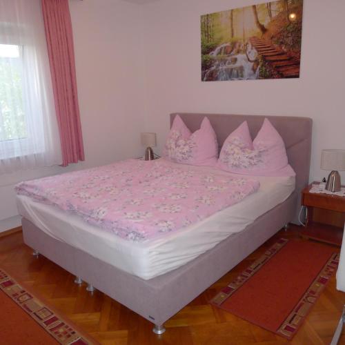 a large bed with pink pillows in a bedroom at Ferienwohnung Kusternik in Velden am Wörthersee