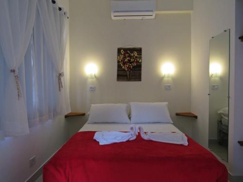 a bed room with a white bedspread and pillows at Pousada do Pinheiro in Camburi