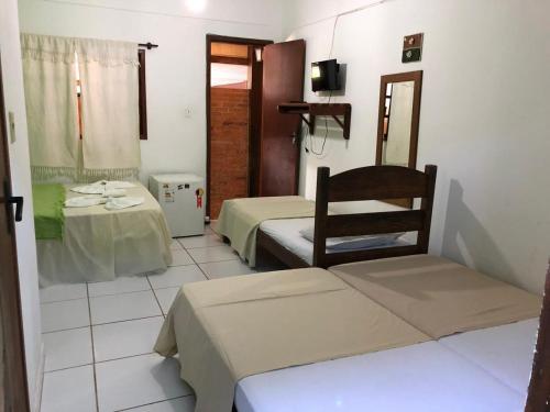 a room with two beds and a chair and a mirror at Pousada Caravelas in Guarapari
