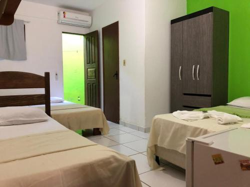 a room with two beds and a green wall at Pousada Caravelas in Guarapari