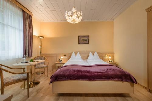 a bedroom with a bed and a table and a chandelier at Hotel Alpenblick in Bad Gastein