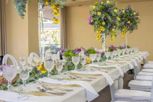 a long table with white chairs and flowers at Movich Hotel de Pereira in Pereira