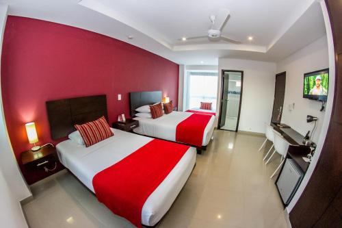 ein Hotelzimmer mit 2 Betten und einer roten Wand in der Unterkunft Hotel Buenos Aires in Cartagena de Indias