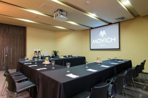 a conference room with tables and chairs and a screen at Movich Hotel de Pereira in Pereira