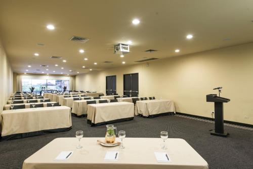 a conference room with white tables and chairs and a podium at Movich Hotel de Pereira in Pereira