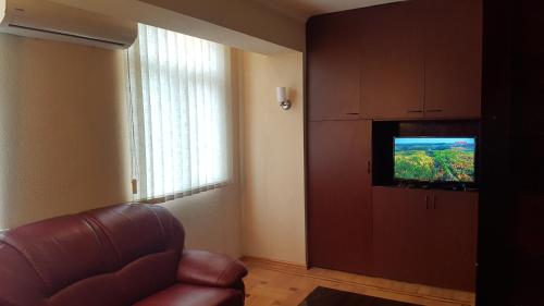 uma sala de estar com uma cadeira de couro e uma televisão em Chekin Imereti em Kutaisi