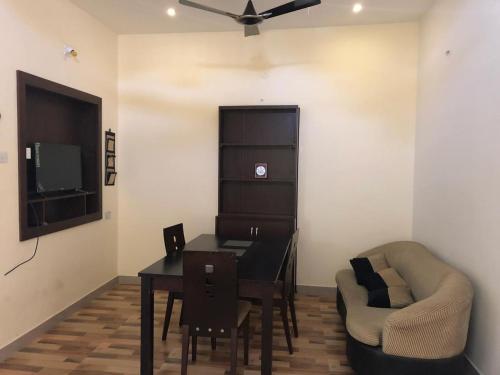 uma sala de estar com uma mesa de jantar e uma cadeira em Castle 50 em Coimbatore