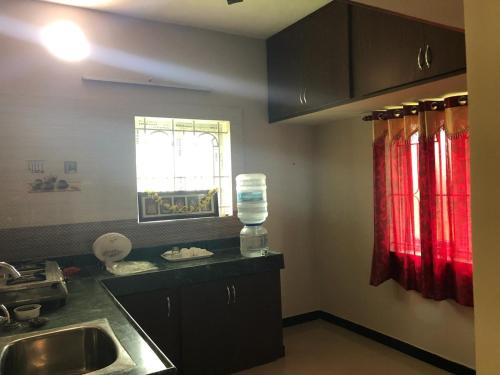 uma cozinha com armários pretos, um lavatório e uma janela em Castle 50 em Coimbatore