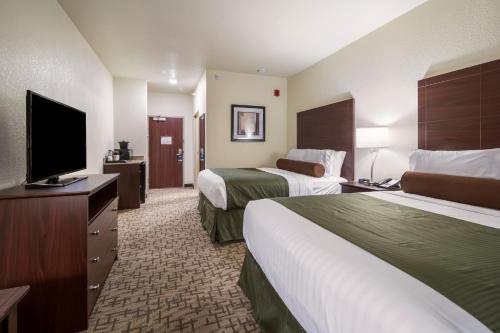 a hotel room with two beds and a flat screen tv at Cobblestone Hotel & Suites - Victor in Victor