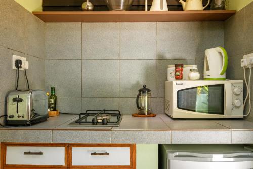 a kitchen counter with a microwave and a stove at Maison Soleil in Baie Lazare Mahé