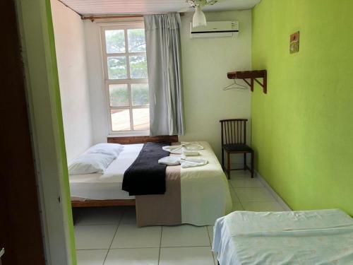 a bedroom with a bed and a window at Pousada Caravelas in Guarapari