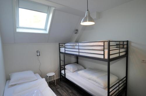 two bunk beds in a small room with a window at Vakantiehuizen 't Centrum in Oostkapelle