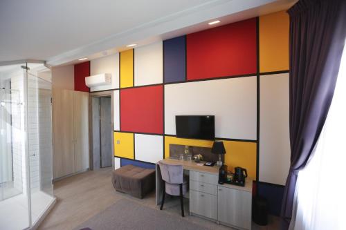 a room with a colorful wall with a desk and a television at Lavender Inn Guest House in Viešvėnai