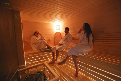a group of three people sitting in a sauna at Lavender Inn Guest House in Viešvėnai