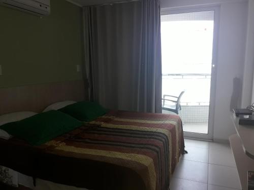 a bedroom with a bed and a large window at Flat à beira mar in João Pessoa