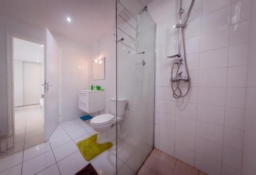 a white bathroom with a shower and a toilet at La vallee de Diane in Petit-Bourg