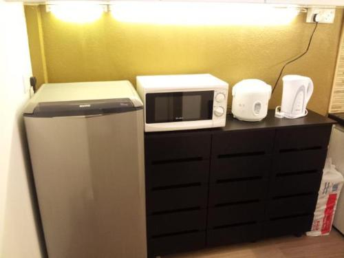 a microwave sitting on top of a counter with a refrigerator at Fastbook Bendera Home 8 & 10pax in Ayer Itam